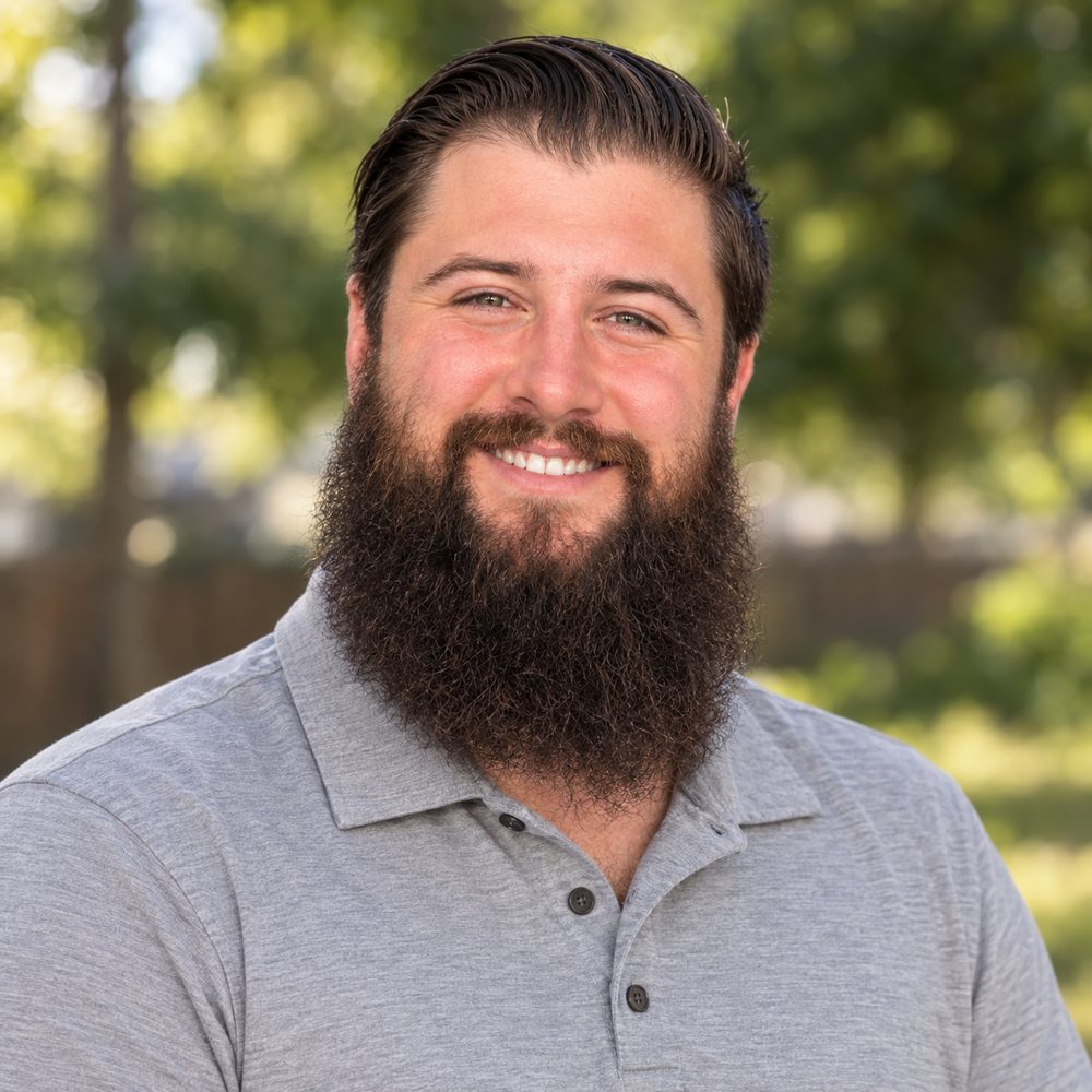 Devin, smiling, in a gray polo outdoors